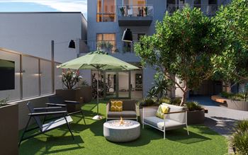 a courtyard with chairs and an umbrella and a fire pit